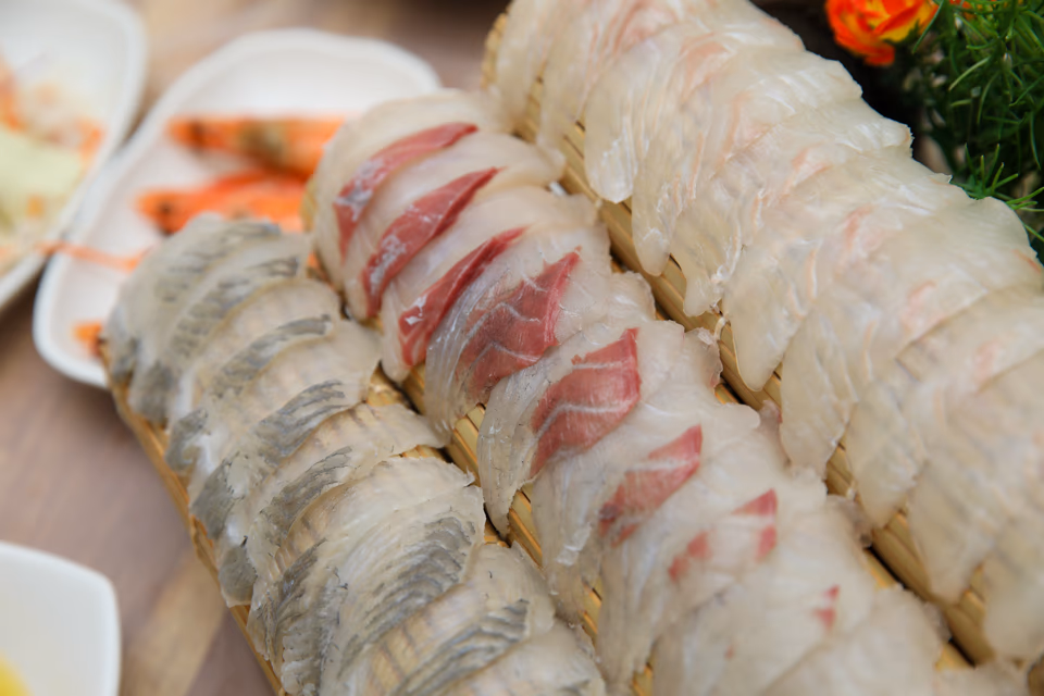 Banchan spread with pickled radish, seaweed, and seasoned vegetables beside sashimi