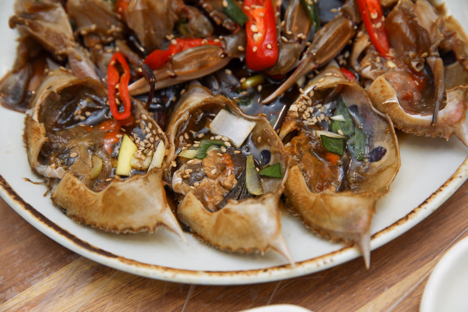 Whole soy-marinated crab on a ceramic plate with soy sauce glaze
