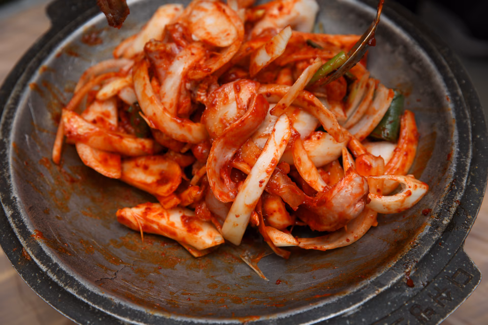 Hagfish pieces sizzling on a briquette grill with smoke rising