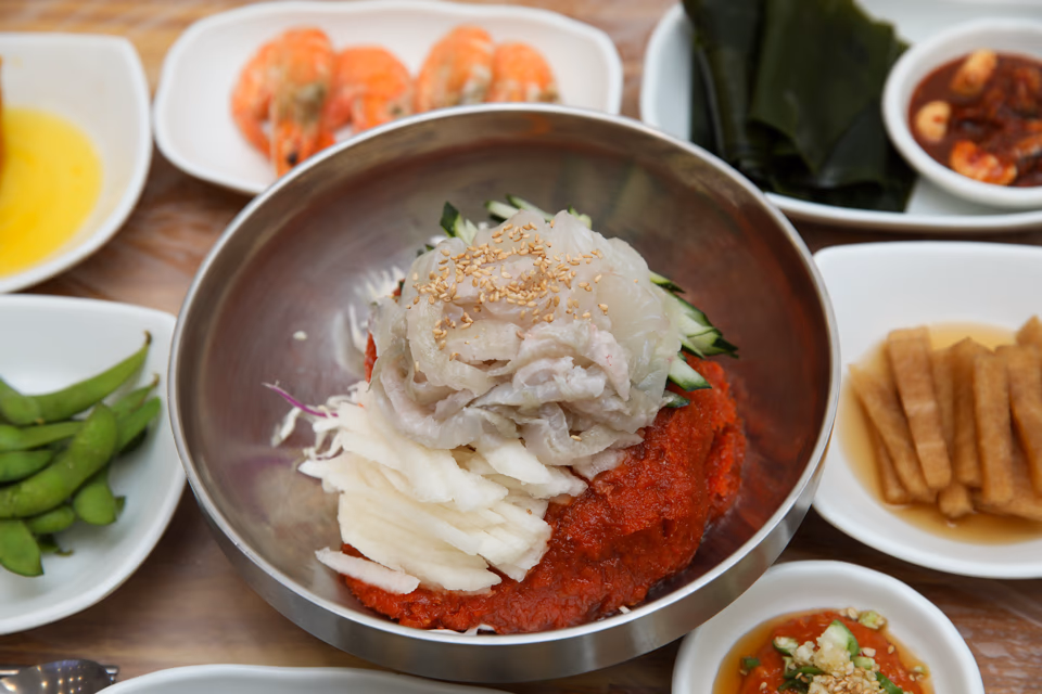 Bowl of mulhoe, raw fish slices in icy red broth with cucumber and noodles