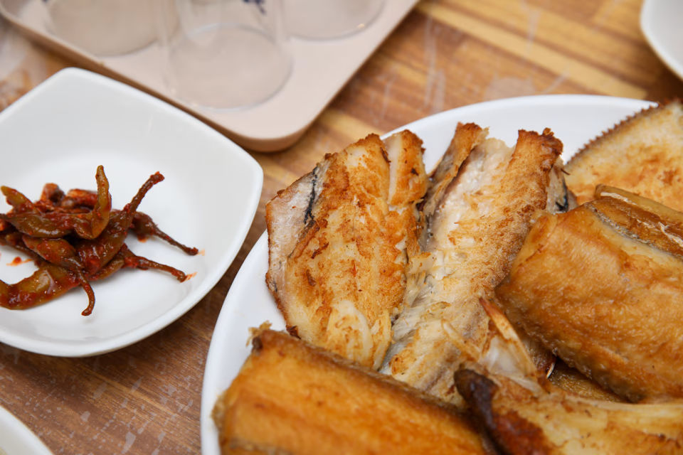 Korean assorted grilled fish platter, several kinds of grilled fish stacked on one plate with side dishes