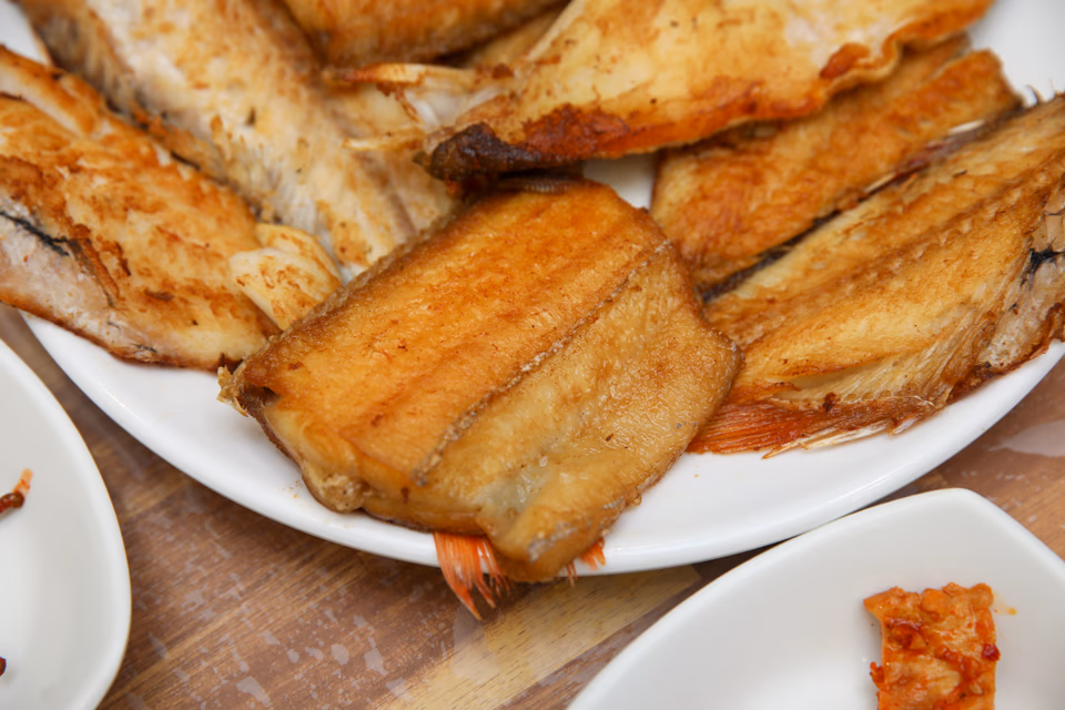 Close-up of assorted grilled fish, hairtail and white fish pieces stacked on a platter