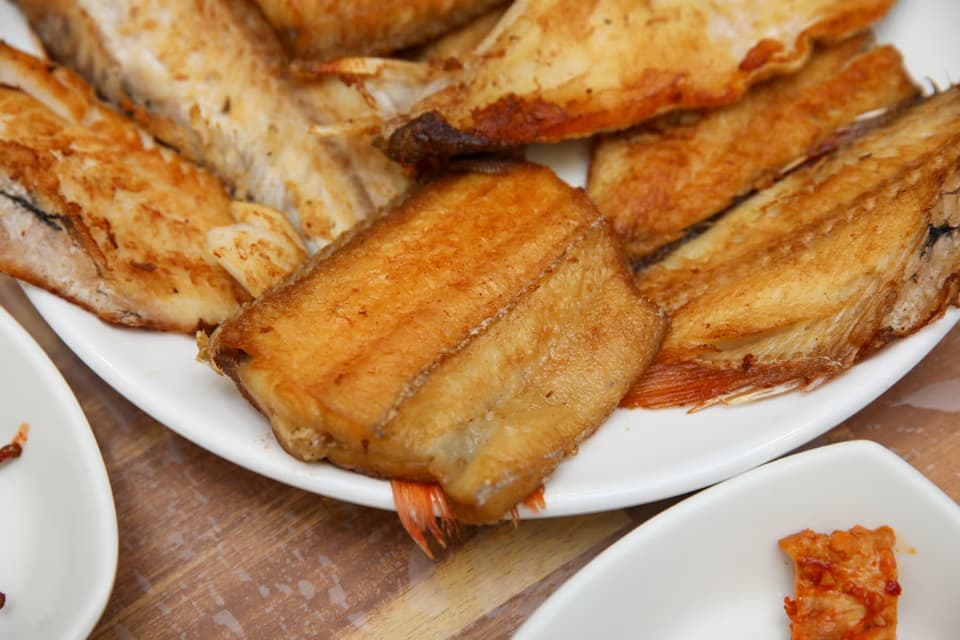 Close-up of assorted grilled fish, hairtail and white fish pieces stacked on a platter