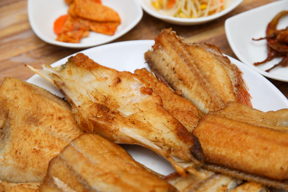 Assorted grilled fish platter components, several fish varieties with rice, soup, and banchan