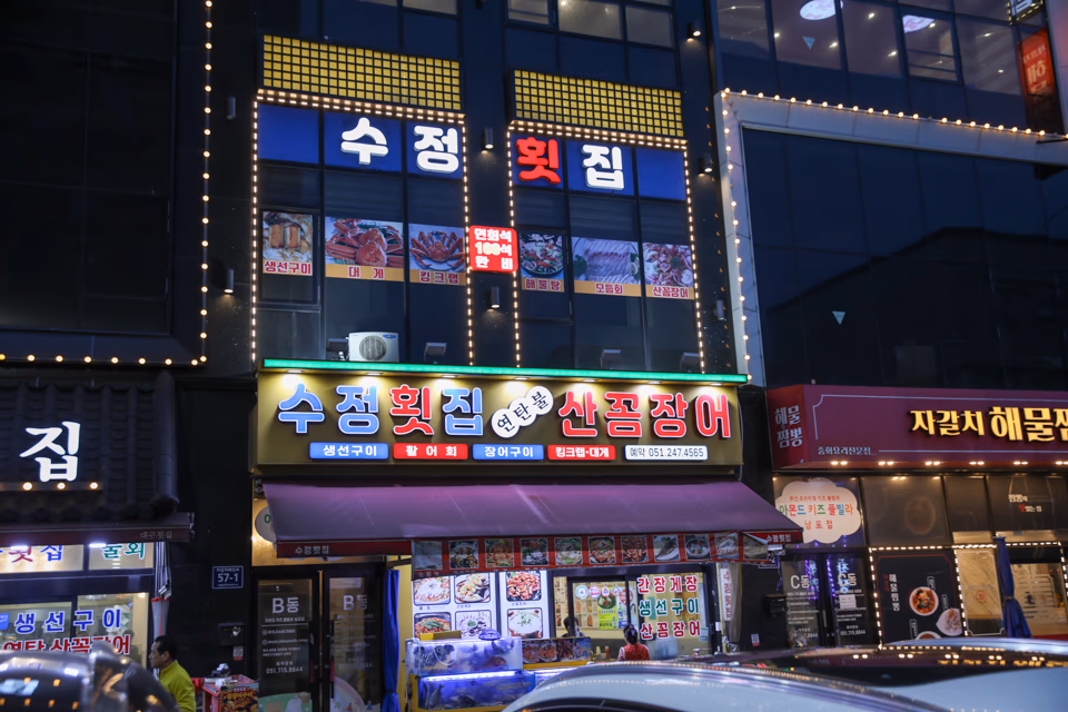 Nampo-dong street scene at dusk with neon signs and pedestrians heading toward dinner