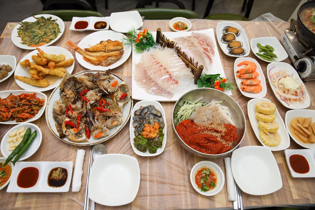 흰살 회와 간장게장, 회무침, 찐 새우, 전복, 튀김, 생선구이가 모두 차려진 한 상 전경