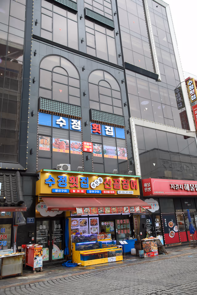 저녁에 불 켜진 가게 정면 간판과 수족관, 그 옆으로 이어지는 1층 출입구
