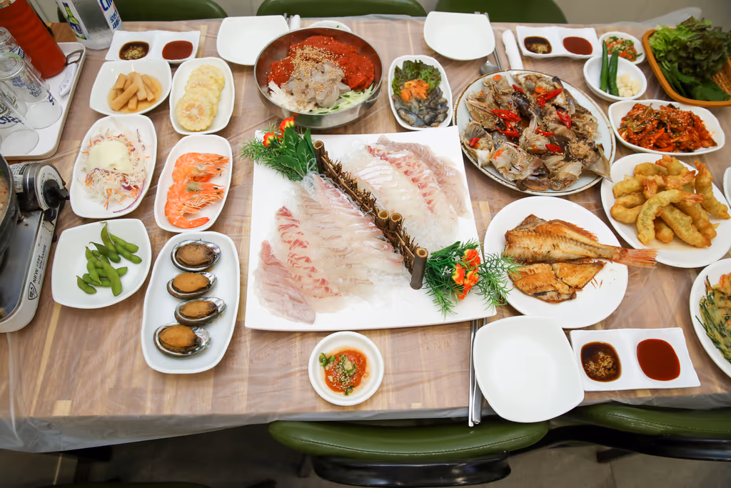 흰살 회와 간장게장, 회무침, 찐 새우, 전복, 튀김, 생선구이가 함께 차려진 자갈치 횟집 한 상 전경