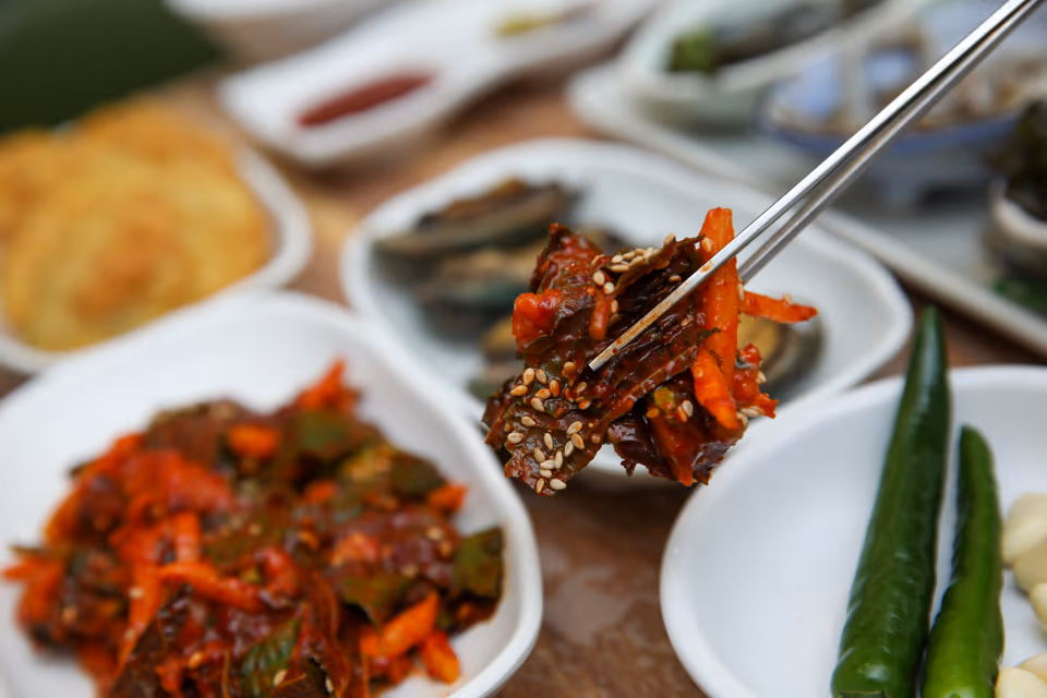 깻잎과 채소, 회를 초고추장에 버무리고 깨를 뿌린 회무침 접시, 옆에 전복과 초장 종지
