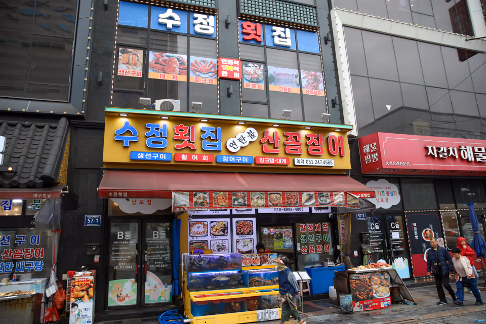 자갈치해안로 횟집 입구 외관, 간판과 유리문이 보이는 거리 모습