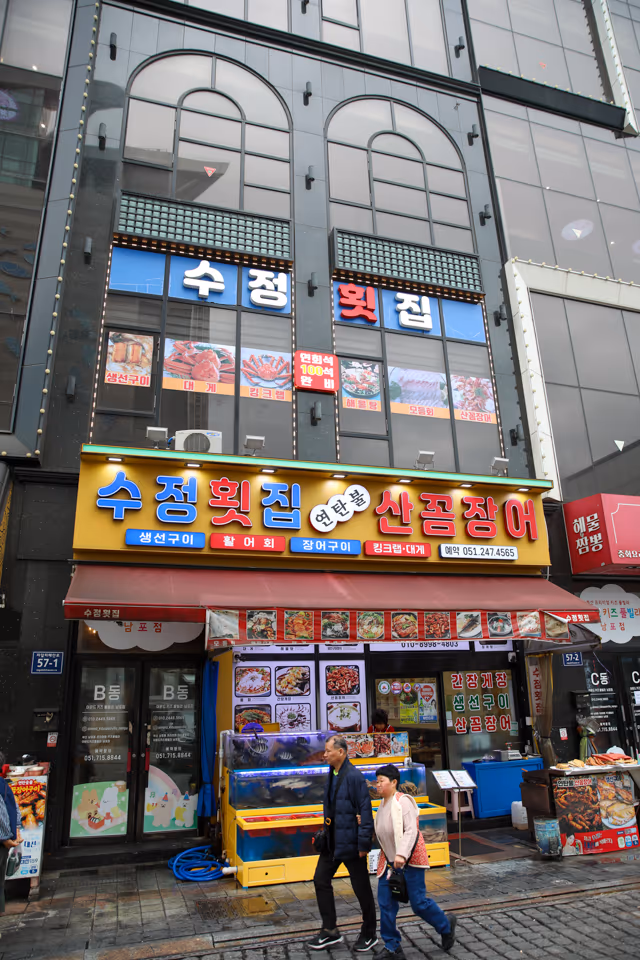 자갈치해안로 횟집 입구와 간판, 유리문 앞에 붙은 안내가 보이는 외관