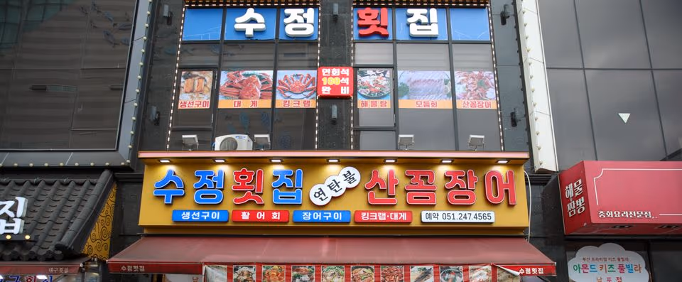 자갈치해안로 식당가 주간 외관, 간판과 메뉴 진열이 보이는 풍경