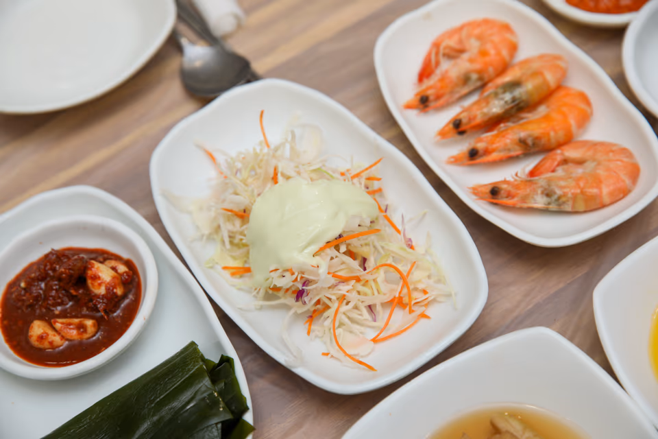 코울슬로, 새우, 깻잎과 초장 종지가 세팅된 횟집 테이블 반찬 구성