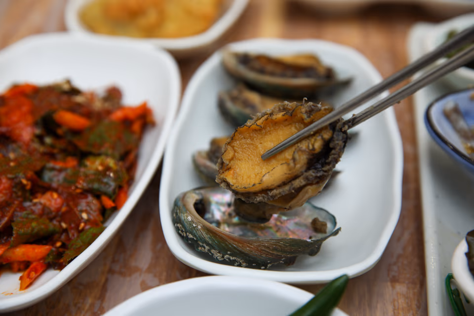 전복찜을 젓가락으로 집어 올리는 클로즈업 장면