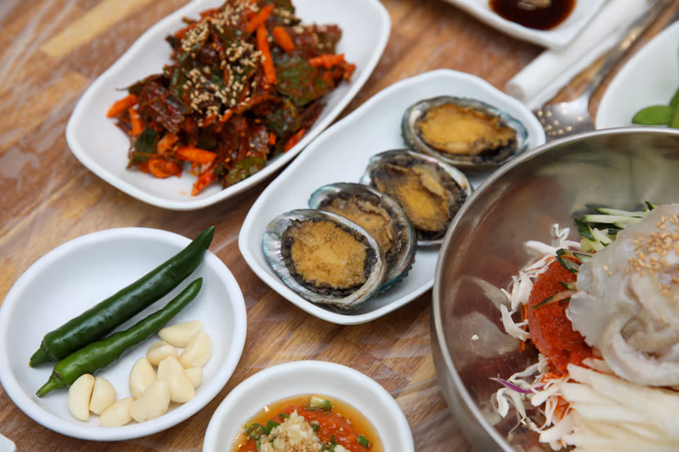 전복구이 단품 접시 실사진, 껍데기째 노릇하게 익힌 전복 세 미가 나란히 놓인 모습
