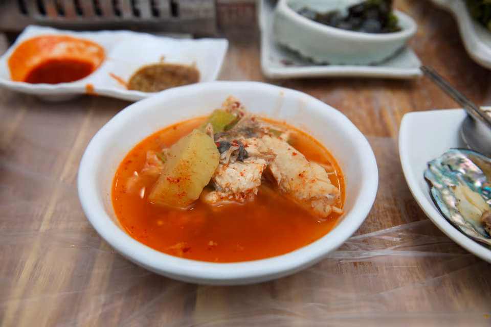 앞접시에 덜어 담은 우럭매운탕 실사진, 우럭 살과 무가 붉은 국물에 잠긴 한 그릇