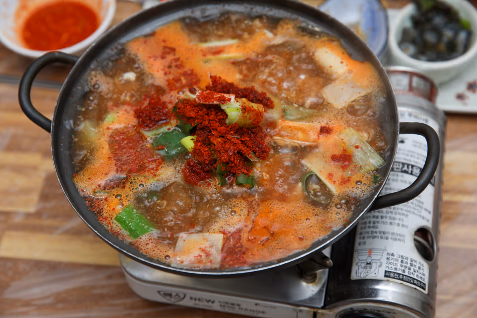 버너 위 냄비에서 끓기 시작한 매운탕 실사진, 고춧가루 양념과 대파 무가 국물 위에 얹힌 초반 상태