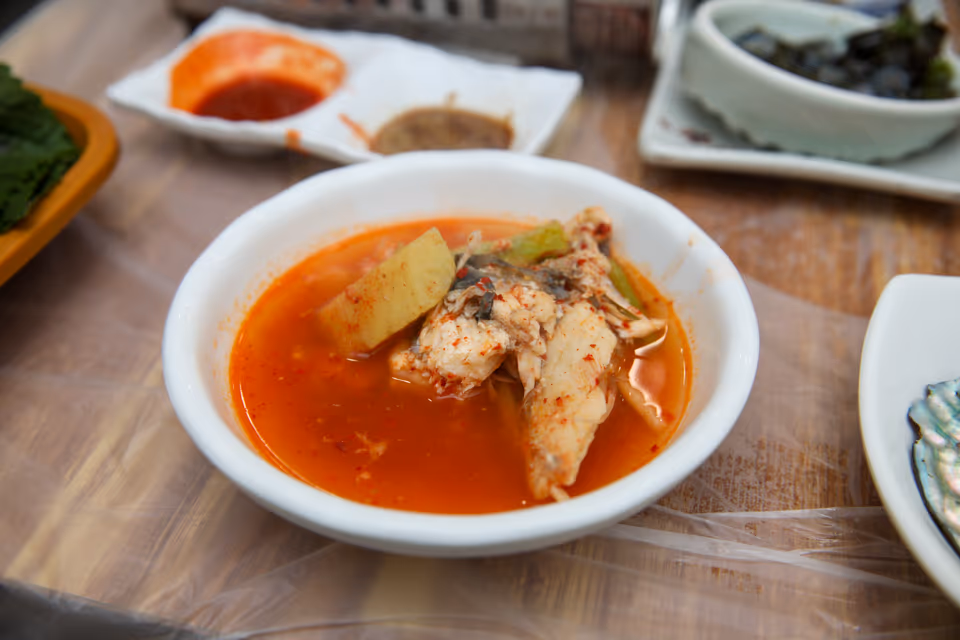 앞접시에 덜어 담은 매운탕 실사진, 생선 살과 무 감자가 붉은 국물에 잠긴 한 그릇