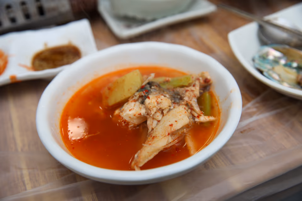 앞접시에 덜어 담은 우럭매운탕, 붉은 국물에 생선 살과 무, 대파가 들어 있는 모습