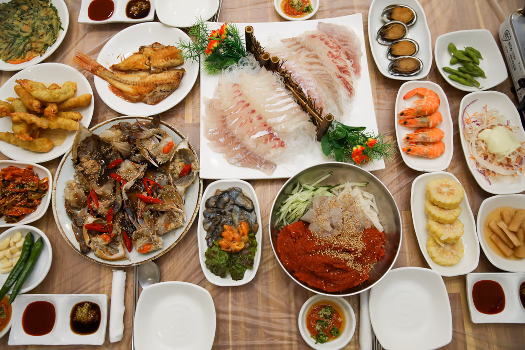 흰살 회와 간장게장, 회무침 대접, 찐 새우, 전복, 튀김, 생선구이가 모두 차려진 상 전경