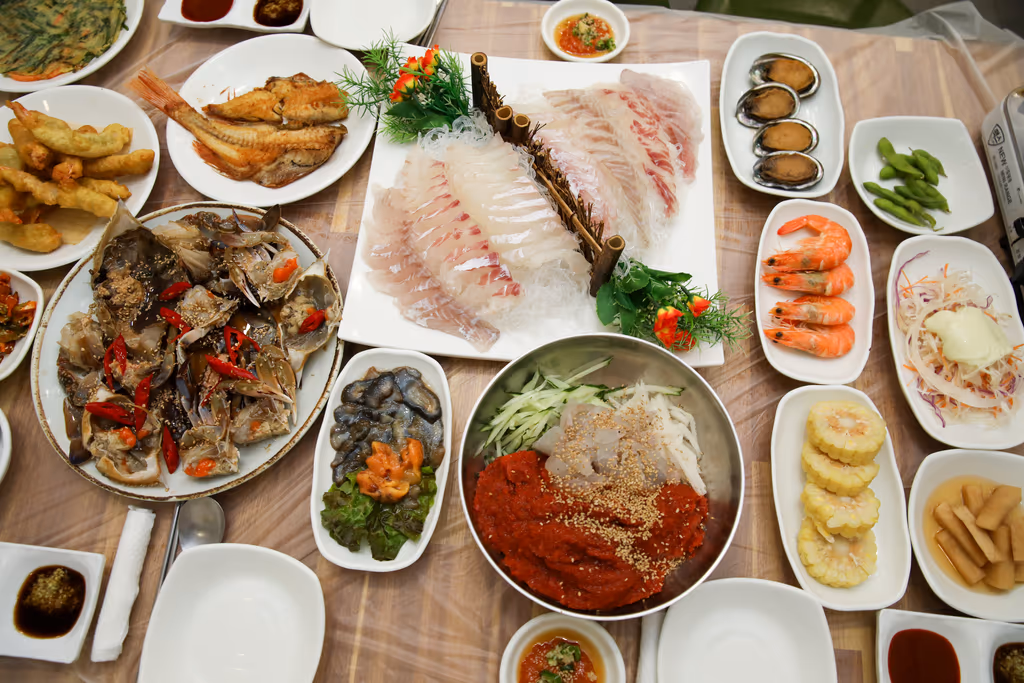흰살 회와 간장게장, 회무침 대접, 찐 새우, 전복, 튀김, 생선구이, 옥수수까지 곁들임이 모두 차려진 자갈치 횟집 한 상 전경