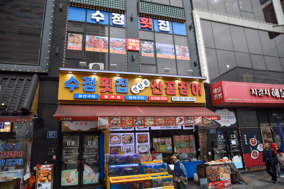 저녁 시간 가게 정면, 연탄불 산꼼장어 간판에 불이 들어오고 수족관과 입구가 보이는 모습