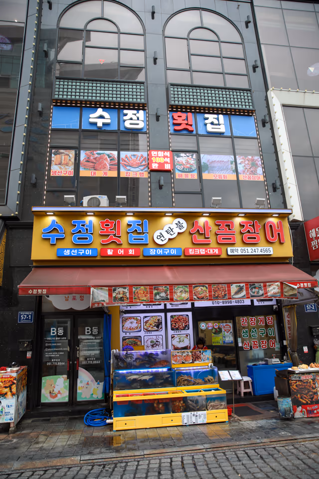 저녁 무렵 가게 정면, 연탄불 산꼼장어 간판 아래 활어 수족관과 입구가 함께 보이는 외관