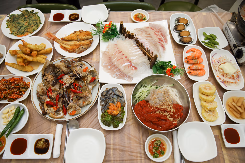 흰살 회와 간장게장, 회무침, 찐 새우, 전복, 튀김, 생선구이가 모두 차려진 한 상 전경